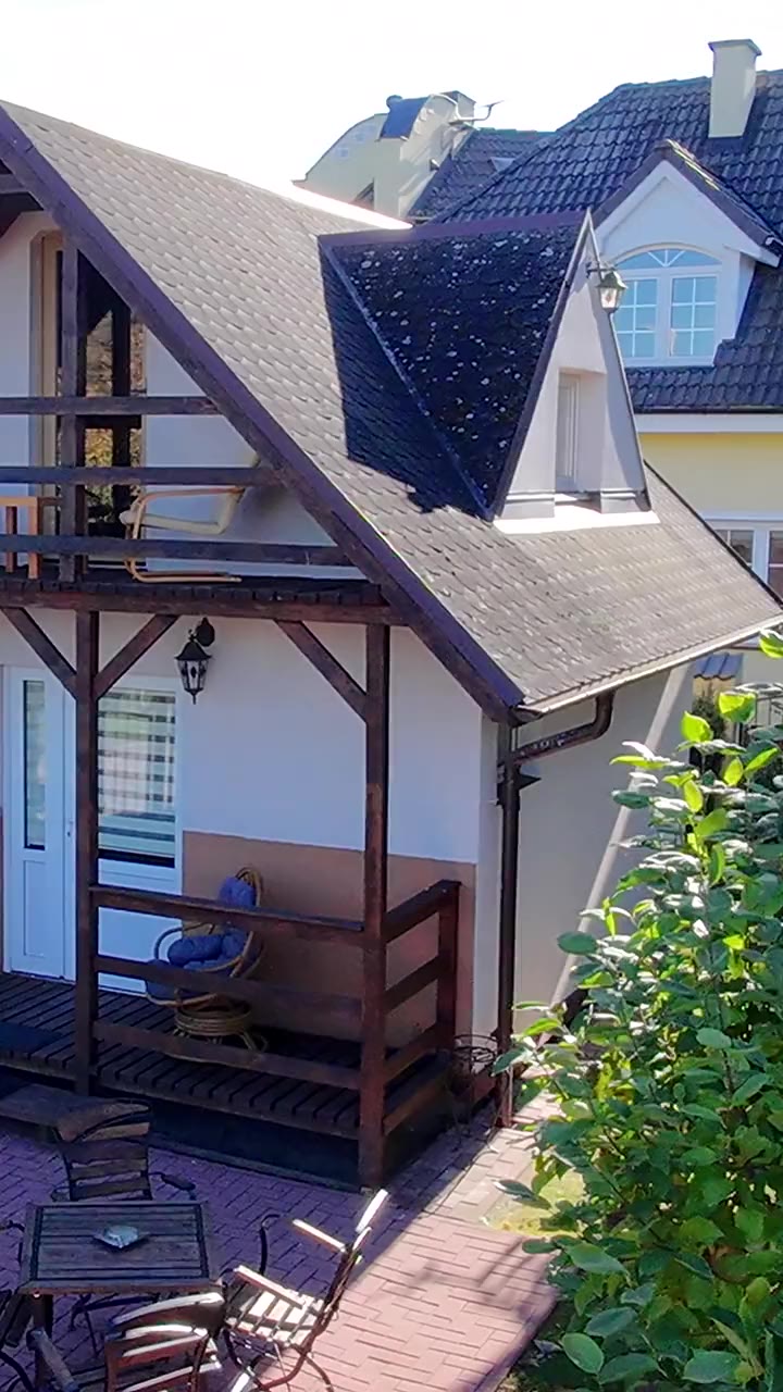 Domek z krytym tarasem i stolikiem w ogrodzie, ujęcie pionowe